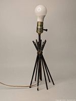 Full view of the bespoke welded metal lamp with a white bulb installed.