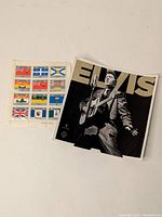USPS sheet of black and white Elvis Presley collectible stamps with a large image of Elvis playing guitar and singing, with 'ELVIS' text