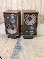 Pair of vintage Jamar Sound AV speakers on black plastic stands. Visible damage on subwoofer cones.