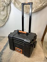 Front view of Ridgid 22-inch Pro Gear Cart Tool Box, showing black body, telescoping handle extended, and orange handle grip.