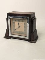 Front view of the vintage wooden mantel clock with square face, metal bezel, and cream dial with black numbers and hands.