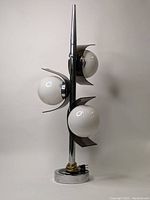 Front view of chrome pole lamp with three white glass globe shades
