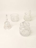 Four items displayed on a plain white background: prayer bell, two sugar bowls (one with lid), and a small pitcher