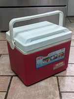 Closed view of red and white vintage cooler showing handle and front label.