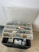 Photo showing open plastic organizer box with multiple compartments holding screws and hardware items