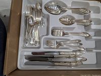 Photo showing variety of silverware pieces including spoons, forks, butter spreaders, and knives neatly arranged in a tray.