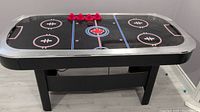 Full front-side view of the air hockey table showing the playing surface, mallets, and puck.