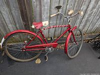 Side view of red Raleigh Space Rider bicycle showing frame, chain guard, rear wheel and seat with some rust and wear.
