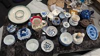 Overview of various bowls, plates, pitchers, and figurines on a dark marble tabletop.