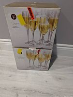 Photo showing two boxed sets of champagne flutes stacked, unopened condition.