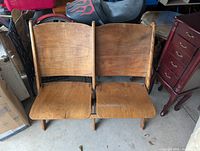 Front view of two connected wooden theatre chairs showing seat and backrest design.