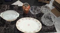 Photo showing all items on table: Pyrex casserole dish, Limoges platter, ceramic vase, three glass bowls