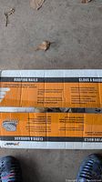 Cardboard box labeled 'Roofing Nails' by Paslode with product info visible on box exterior and a foot for scale.