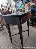 Side view showing the drawer and leg structure of the wooden side table.