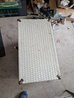 Top view of the closed wicker and wood chest showing corner protectors and surface texture.