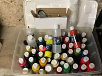 Photo showing multiple bottles of airbrush paints in a variety of colors arranged in a plastic storage bin.