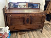 Front view of antique wooden buffet with mirror, showing two drawers, locking cupboard doors with key, and bottom drawer