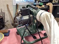 Left-side view showing motor housing, handle, fabric bag and caster wheels