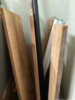 Several barn board wooden planks leaning against a wall, showing rough and smooth worn edges.