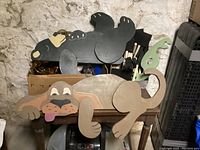 Wooden black bear and brown dog fence rail sitters on a small table indoors.