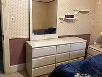 Dresser with attached mirror and part of bed with nightstand visible