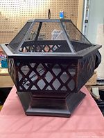 Front and side view of the metal hexagonal outdoor fireplace showing diamond mesh pattern and sturdy base.
