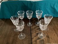 Front view of 7 red wine glasses arranged on a wooden table showcasing the cut pattern on bowls.
