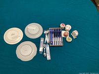 Photo showing three sandwich plates (two Menuet Japanese 22 carat gold and one British Empire ceramic), six pickle forks, four small floral trinket boxes, napkin holder, and two decorative boxed spoons.