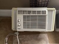 Photo of the Black & Decker 5000 BTU window air conditioner, front view showing manual dials and front grille, with side accordion window panels extended.