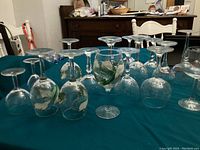 Multiple assorted wine glasses arranged on teal tablecloth showing various sizes and shapes.
