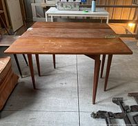 Photo of the antique wooden drop leaf table fully open showing surface wear.