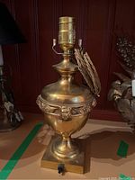 Full view of vintage brass lamp showing urn-shaped body and rope-covered cord wrapped around lamp neck.