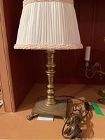 Full view of brass lamp with antique fabric pleated shade showing overall design and proportions.