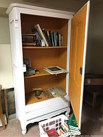 Front view of open armoire showing orange interior shelves and missing door hardware