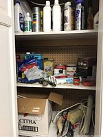 Shelf with assorted wood care products, paint cans, caulking tubes, scrapers, and small supplies visible