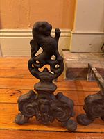 Front and side views of one cast iron andiron showing lion figure and detailed base.