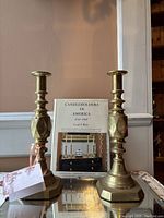 Photo showing a pair of English brass candlesticks and a book about American candleholders.