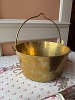 Full side view with handle up showing the pot's shape and brass shine.