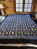 Full view of quilt laid out on bed showing overall square patchwork design and borders