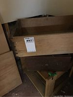 Old wooden drawer with visible dovetail joints placed on a small wooden stool, part of the lot.