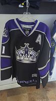 Front view of black and purple Los Angeles Kings Reebok NHL hockey jersey with crown logo and 'A' patch.