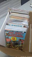 Box open displaying various loose Marvel and DC comic books in protective bags