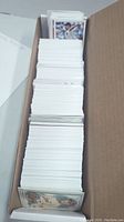 Top view showing a large number of modern baseball cards in white bordered style with some holographic cards near front.