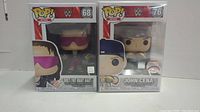 Front view of two WWE Funko Pop figures in original sealed packaging, showing Bret Hart and John Cena.