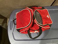 Red Adidas duffle bag showing multiple compartments including cooler compartment with mesh and shoe compartment.