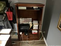 Front view of the Arhaus wooden armoire cabinet showing open middle section with shelves and drawers, with various office items inside that are not included.