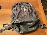 Gray Under Armour basketball backpack on wooden table showing front and bottom ball pocket