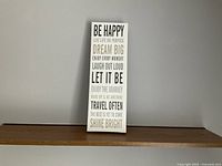 Front view of the Be Happy poster frame showing the full text and design on a white background with black fonts.