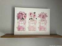 Photo of the Chanel poster featuring three perfume bottles with pink flowers inside each bottle.