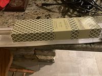 Close-up photo of the packaged drapery rod wrapped in green and white patterned paper with label.